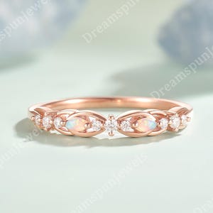 May include: Rose gold ring with opal and diamond detailing. The ring showcases a delicate design with oval opal stones and small round diamonds. The gemstones are arranged in a repeating pattern along the band, creating a sparkling and elegant appearance.
