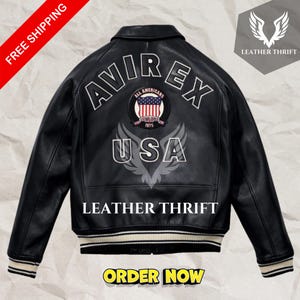 Könnte beinhalten: Schwarze Lederbomberjacke mit einem weißen und schwarzen gerippten Kragen und Bündchen. Die Jacke hat einen großen gestickten Aufnäher auf der Rückseite, auf dem "AVIREX ALL AMERICANS ESTABLISHED 1975 USA" mit einer rot-weiß-blauen amerikanischen Flagge in der Mitte steht. Der Text "LEATHER THRIFT" ist unter dem Aufnäher gedruckt.