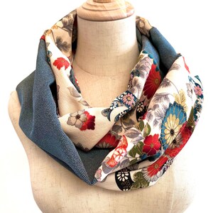 Könnte beinhalten: Ein reversibler Infinity-Schal aus recyceltem japanischem Kimono-Stoff. Eine Seite zeigt ein blaues und weißes geometrisches Muster, während die andere Seite ein florales Design mit roten, weißen und goldenen Akzenten aufweist.