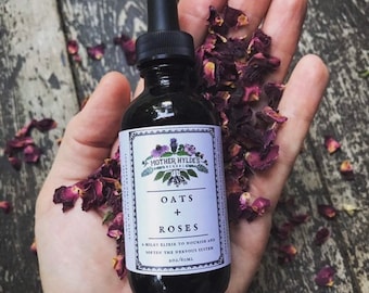 Könnte beinhalten: Eine dunkle Glasflasche mit einer Pipette, beschriftet mit "Oats + Roses" mit dem Text "Mother Hyldes Herbal". Die Flasche wird in einer Hand mit getrockneten Rosenblättern gehalten. Das Etikett lautet auch "Ein milchiger Elixier zur Ernährung und Beruhigung des Nervensystems 60 ml".