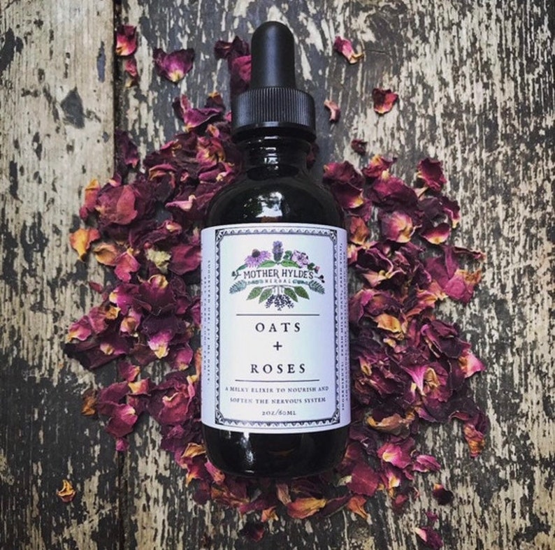 May include: A dark glass bottle with a dropper, labeled "Oats + Roses" surrounded by dried rose petals. The label reads "Mother Hyldes Herbal" and "A milky elixir to nourish and soften the nervous system". The bottle contains 2 oz / 60 ml.