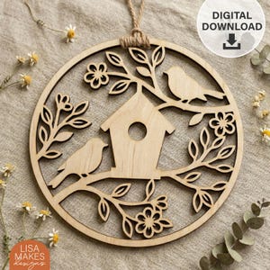 May include: A wooden circular ornament featuring a birdhouse, two birds, and floral and leaf accents. The design is laser-cut from light-colored wood and includes the text "DIGITAL DOWNLOAD". A jute twine loop is attached for hanging. The text "LISA MAKES designs" is also visible.