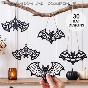 May include: Five black laser-cut bat ornaments with intricate filigree, web, and floral patterns, each suspended by a thin jute twine string. The text INSTANT DOWNLOAD, COMMERCIAL USE, and 30 BAT DESIGNS are visible in the image.