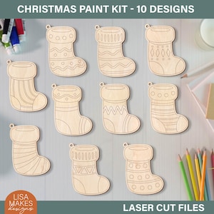 May include: A Christmas paint kit with 10 laser-cut wooden stocking designs. Each stocking has a unique pattern, ready for painting. The kit includes the text "CHRISTMAS PAINT KIT - 10 DESIGNS" and "LASER CUT FILES". The Lisa Makes Designs logo is also visible.