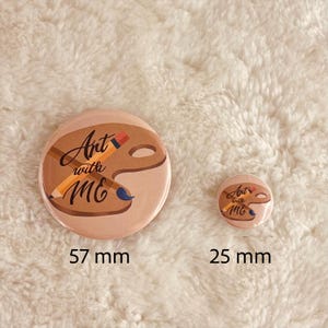 May include: Two round buttons with the text "Art with Me" and a paint palette and pencil design. The larger button is 57 mm in diameter and the smaller button is 25 mm in diameter.