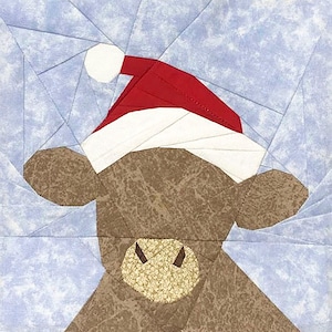 Puede incluir: Diseño de patchwork de una vaca marrón con un gorro de Papá Noel rojo y blanco. La vaca tiene un hocico beige texturizado y cuernos oscuros. El fondo es un patrón geométrico azul claro.