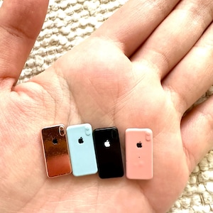 May include: Four miniature plastic iPhone models in different colors: rose gold, light blue, black, and pink.
