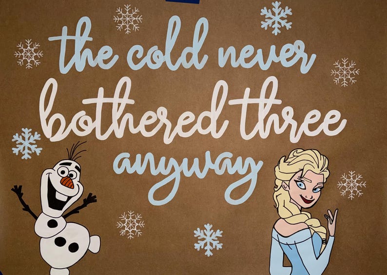May include: A brown background with the phrase "the cold never bothered three anyway" in white and light blue script. The image features cartoon illustrations of Olaf the snowman and Elsa from the movie Frozen, along with snowflake accents.