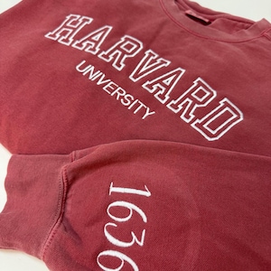 May include: A maroon sweatshirt with white embroidered text that reads "Harvard University" and "1636" on the sleeve.