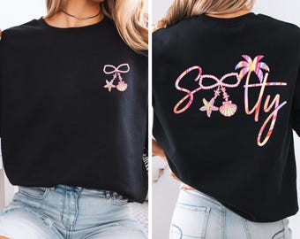 May include: Black sweatshirt with a colorful "Softy" design on the back, featuring a bow, starfish, and seashell. The front has a smaller version of the design. The sweatshirt is made of Gildan Black material.