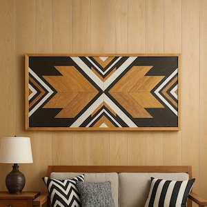 Op de afbeelding: Een geometrisch houten kunstwerk met een omlijnd ontwerp in zwart, wit en bruintinten hangt boven een beige bank met decoratieve kussens. Een houten salontafel bevat een kom met dennenappels en een mok.