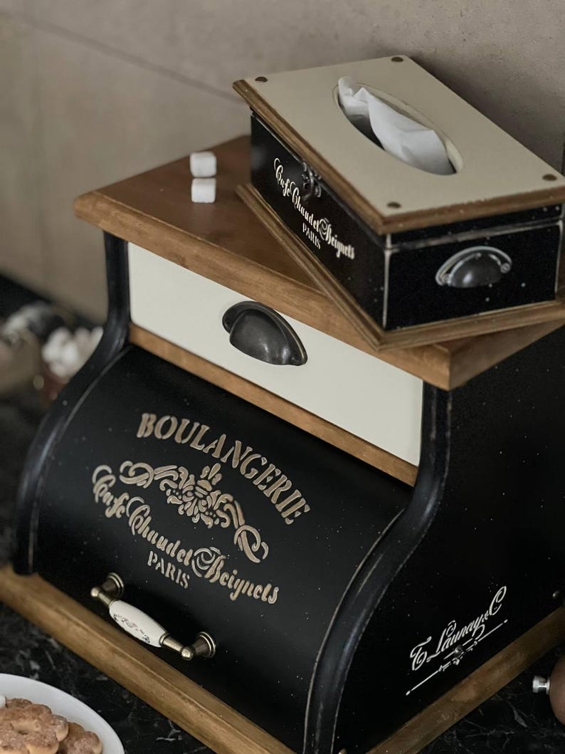Puede incluir: Un juego de caja de pa&ntilde;uelos y pan negro y madera con el texto "Cafe Chaudet Beignets PARIS" y "BOULANGERIE Cafe Chaudet Beignets PARIS". El juego tiene una est&eacute;tica vintage con tiradores de metal y un caj&oacute;n blanco.