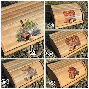 Op de afbeelding: Houten broodtrommels met roldeksels. Elke doos heeft een andere decoratieve afbeelding: kruiden, gebak, een pot jam en gebak met aardbeien. De dozen zijn gemaakt van lichtgekleurd hout.