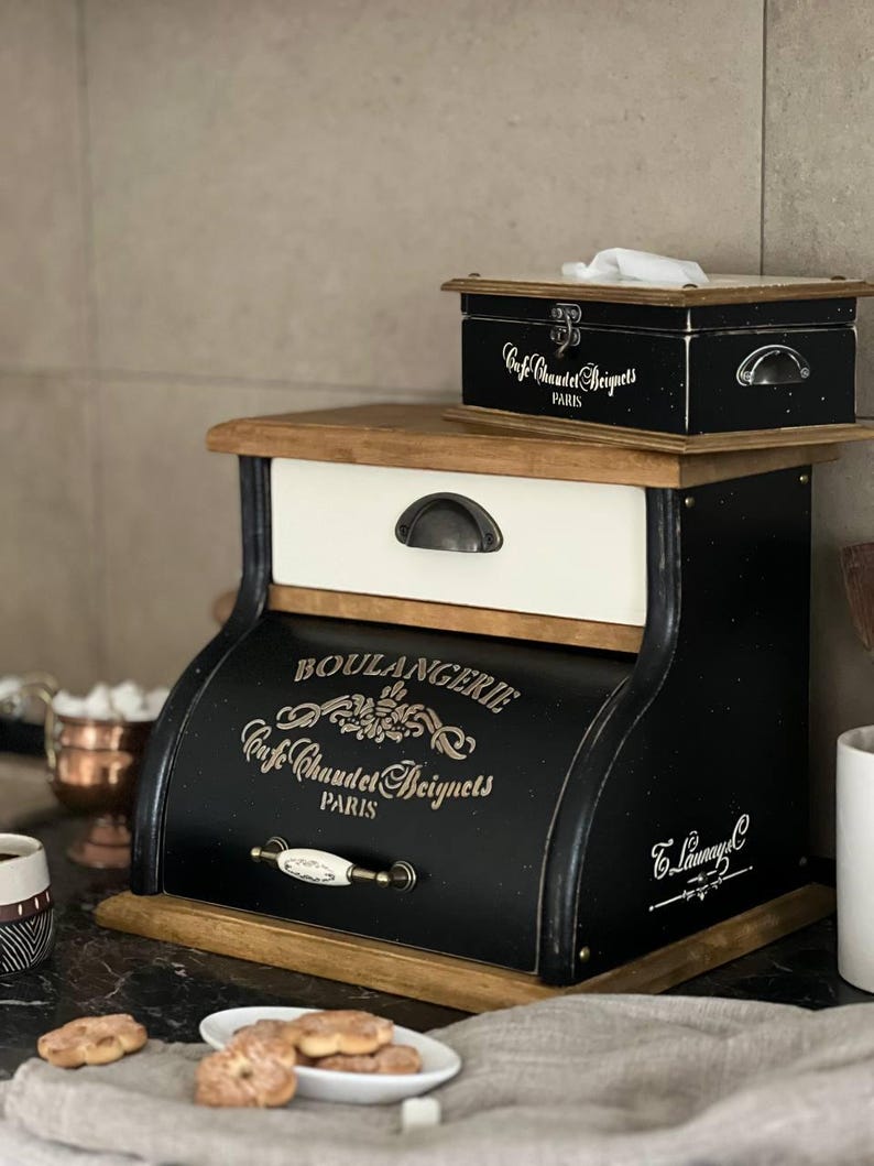 Puede incluir: Una panera de madera en blanco y negro con las palabras "BOULANGERIE Cafe Chaudet Beignets PARIS" impresas en la parte delantera. Una caja negra m&aacute;s peque&ntilde;a con el mismo texto se encuentra encima. La panera tiene un caj&oacute;n blanco y una tapa de madera.