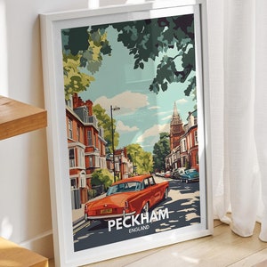 Peut inclure: Une affiche encadrée blanche avec une illustration colorée d'une scène de rue à Peckham, en Angleterre. L'affiche représente une voiture rouge roulant dans la rue, avec des bâtiments et des arbres en arrière-plan. Le texte "PECKHAM, ENGLAND" est imprimé en bas de l'affiche.