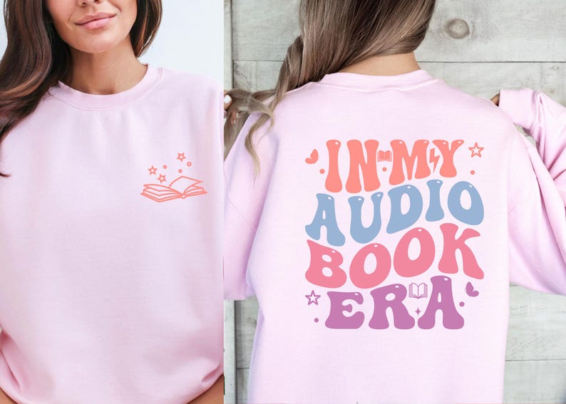 a woman wearing a pink sweatshirt with the words in my audio book era printed on