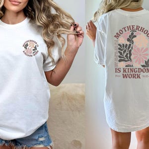 May include: White t-shirt with a floral design and the text "Motherhood is Kingdom Work Prov. 31:25-27" on the back.