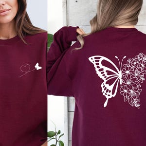 a woman wearing a maroon sweatshirt with a butterfly on it