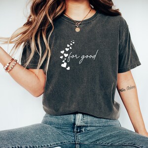 May include: A dark gray t-shirt with a white graphic of hearts and the text "for good".