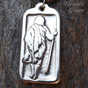 May include: Silver pendant necklace featuring a detailed image of a person walking with a staff. The pendant is rectangular and has a smooth, polished finish. The text "Your Inner Path" is engraved below the image.