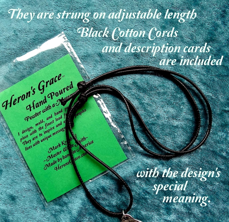 May include: A black cotton cord necklace with a pewter pendant that says "Heron's Grace Hand Poured". The pendant is attached to a green card with the text "Pewter with a message I design, mold, and hand pour each piece with the finest lead free pewter. They are to inspire and encourage lives with unique messages. Mark Kroh - Master Wire Smith - Made by hand in America Heron'sGrace.com". The card is in a clear plastic bag. The text "They are strung on adjustable length Black Cotton Cords and description cards are included with the design's special meaning." is written above the image.