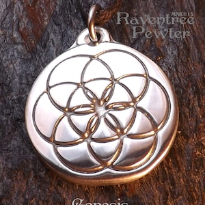 May include: Silver pendant featuring a detailed Flower of Life design. The pendant is round and has a loop at the top for attaching a chain. The pendant is engraved with the word "Genesis".