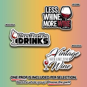 May include: Three wine-themed stickers with white borders. One reads "Less Whine, More Wine" with a wine glass. Another says "Here For The Drinks" with a wine glass. The third says "Vintage Wine" with a wine bottle and glass.