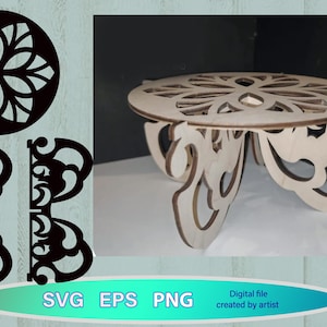 Peut inclure: Un présentoir à gâteau en bois découpé au laser avec un motif floral complexe sur le dessus et des pieds décoratifs. Le présentoir est brun clair et a un dessus rond. L'image comprend également les formats de fichiers SVG, EPS et PNG.