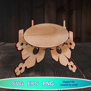 Könnte beinhalten: Holzständer mit runder Oberseite und filigranen Blumendesigns. Der Ständer ist aus hellbraunem Holz gefertigt und hat eine natürliche Oberfläche.