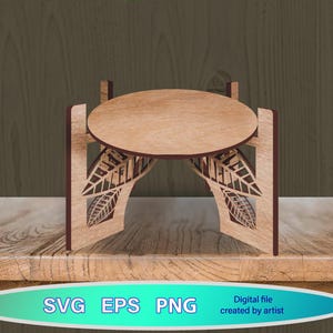Pode incluir: Um suporte decorativo de madeira com um tampo oval e recortes em forma de folha. O suporte é feito de madeira castanha clara com detalhes em castanho escuro. A imagem também inclui o texto "SVG EPS PNG".
