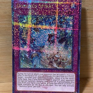 May include: A holographic trading card with the title "DOMINUS SPIRAL" at the top. The card features a detailed illustration with a dark, fantasy theme. The card's text describes its effects and activation conditions.