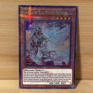 Puede incluir: Una tarjeta coleccionable holográfica con borde rojo oscuro, que presenta al personaje "Fallen of the White Dragon". La tarjeta muestra una ilustración detallada de un personaje con cabello y ropa blancos. El texto de la tarjeta incluye instrucciones del juego.