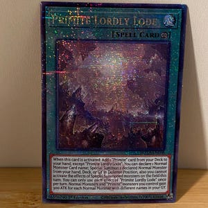 May include: A holographic trading card for the game Yu-Gi-Oh! featuring the spell card "Primite Lordly Lode". The card has a purple and blue background with a white border. The card text describes the card's effect, which allows the player to add a "Primite" card from their deck to their hand and special summon a normal monster.