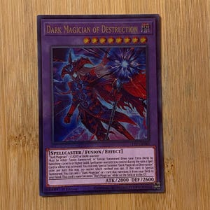 Peut inclure: Une carte &agrave; collectionner Yu-Gi-Oh! Dark Magician of Destruction. La carte pr&eacute;sente une illustration sombre d'une figure ressemblant &agrave; un magicien avec un b&acirc;ton. Le texte de la carte comprend son nom, ses attributs et ses effets. Attaque 2800, D&eacute;fense 2600.