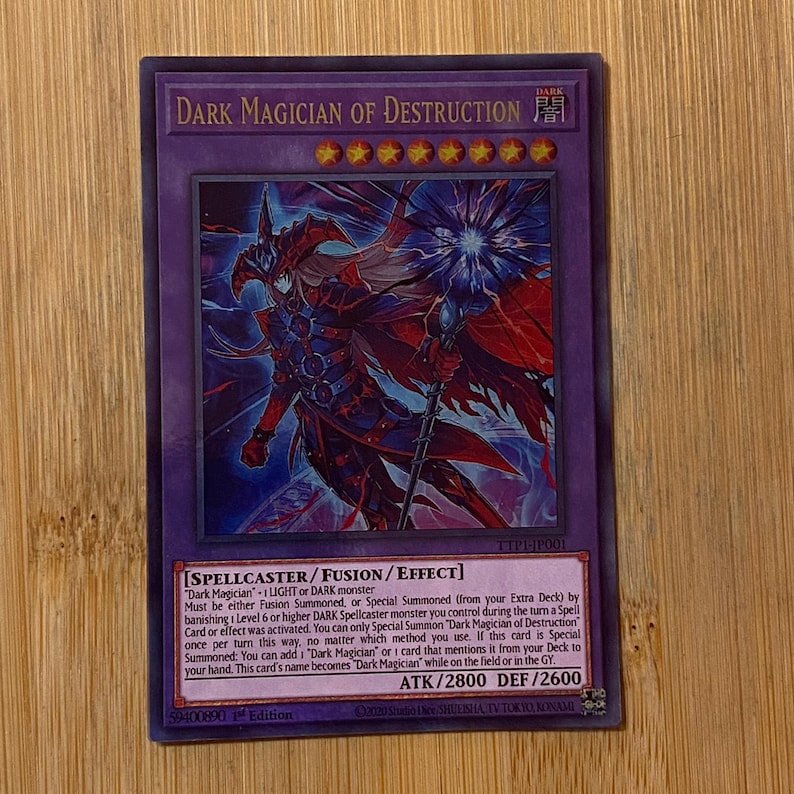 Peut inclure: Une carte &agrave; collectionner Yu-Gi-Oh! Dark Magician of Destruction. La carte pr&eacute;sente une illustration sombre d'une figure ressemblant &agrave; un magicien avec un b&acirc;ton. Le texte de la carte comprend son nom, ses attributs et ses effets. Attaque 2800, D&eacute;fense 2600.