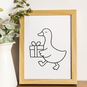 May include: A framed art print featuring a black and white line drawing of a duck carrying a gift box. The duck is smiling and walking, with the gift box held in its wing. The artwork is in a light brown wooden frame.