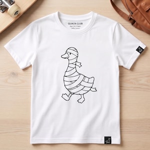 May include: A white short-sleeve t-shirt featuring a black line art graphic of a duck wrapped in bandages like a mummy. The inner neck label reads QUACK CLUB, Age 10-12 Years, 100% Cotton. A small black tag with a duck icon is on the sleeve and hem.