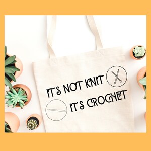May include: White canvas tote bag with the text "It's not knit, it's crochet" in black. The bag has two icons, one of a crochet hook and the other of knitting needles.