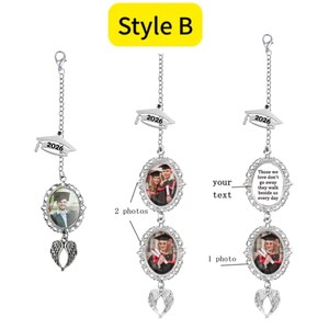 May include: Silver graduation photo car charm with a cap charm that reads "2026". The charm has an oval photo frame and angel wing charm. The charm can hold one or two photos. The text "Those we love don't go away they walk beside us every day" is also available.