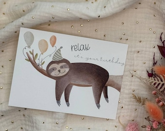 May include: A birthday card featuring a watercolor illustration of a sloth wearing a party hat and holding balloons. The card reads "relax it's your Birthday" in a handwritten font. The sloth is brown and gray, with beige and gray balloons.