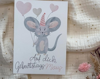 May include: A birthday card featuring a watercolor illustration of a gray mouse holding heart-shaped balloons. The mouse wears a party hat and the card has the text "Auf dich, Geburtstag Maus" in script.