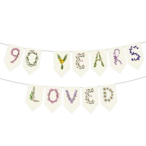 May include: A banner with the words "90 YEARS LOVED" spelled out on individual cream-colored pennants. The letters and numbers are decorated with various flowers and greenery, creating a floral design.