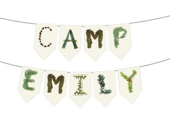May include: A banner with the word "CAMP EMILY" spelled out on individual cream-colored pennants. The letters are decorated with natural elements like twigs and leaves, creating a rustic, outdoorsy aesthetic.