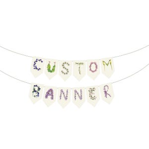 May include: A custom banner with the word "CUSTOM BANNER" spelled out on individual cream-colored pennants. Each letter is formed with colorful flowers and foliage, strung on a thin wire against a white background.