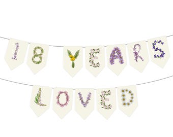 May include: A banner with the words "18 YEARS LOVED" spelled out with floral letters. The banner is made of off-white pennants strung together with a thin wire. The flowers are in shades of purple, yellow, and white.