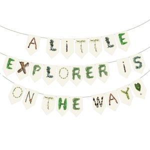 K&ouml;nnte beinhalten: Ein Banner mit drei Reihen Wimpeln, die an einem d&uuml;nnen Draht aufgereiht sind. Die cremefarbenen Wimpel zeigen die Worte "A LITTLE EXPLORER IS ON THE WAY" in dekorativen gr&uuml;nen und braunen Schriftarten, ideal f&uuml;r eine Babyparty.