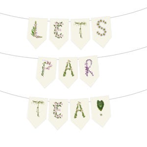A floral banner with the words 'Lets Par Tea spelled out using wild flowers. The O is with pink obedient flowers, the L with licorice flowers, I with sage, V with purple violets, R with redbuds and Y with yellow yarrow. The banner is made of a very light cream paper and there is a string running through the top. The letters are on individual rectangular papers with pointed tips. It has a rustic, cottage garden boho vibe.