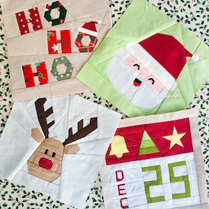 以下が含まれることがあります： クリスマスをテーマにした手作り生地の正方形が4つ、それぞれ異なるデザインです。最初の正方形には、赤と緑の生地の文字で「Ho Ho Ho」と書かれています。2番目の正方形には、赤い帽子をかぶったサンタクロースの顔が描かれています。3番目の正方形には、茶色の角を持つトナカイが描かれています。4番目の正方形は赤い背景に、緑のクリスマスツリー、金のベル、星、そして「DEC 25」の文字が書かれています。