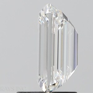 May include: A clear, rectangular emerald cut diamond with a brilliant finish. The diamond is set in a prong setting and is on a white background.