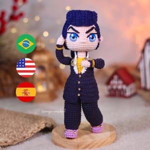 May include: Crocheted amigurumi doll of a character with blue hair, a yellow shirt, and a dark blue suit. The doll is standing on a wooden base. The doll is wearing purple shoes with gold accents. The doll is holding its hand to its head. The doll is standing in front of a background with a red and white striped flag, a blue and white striped flag, and a green, yellow, and blue flag.
